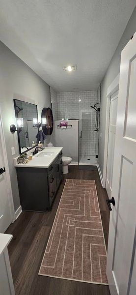 Bathroom with dark vanity, white tile shower, and herringbone rug.