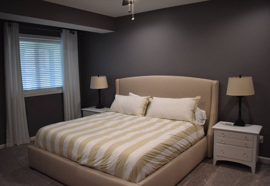 Bedroom with bed, nightstands, lamps, window, and dark gray walls.