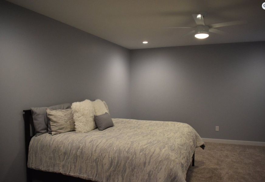 Bedroom with a gray bed, gray walls, and a ceiling fan.