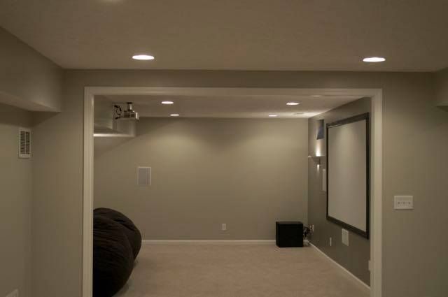Home theater room with projector, screen, and recessed lighting. Beige walls and carpet.