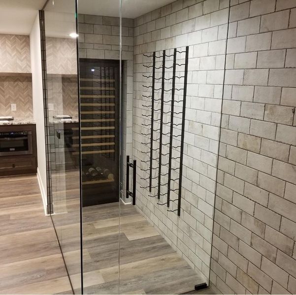 Wine storage room with glass door. Brick wall, rack for wine bottles, wooden floor.
