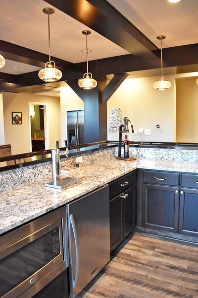 Kitchen with granite countertops, dark cabinets, stainless steel appliances, and wood beams.