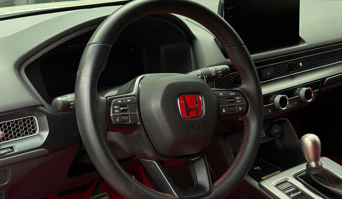 Car interior with Honda steering wheel, dashboard vents, and center console in black and silver.