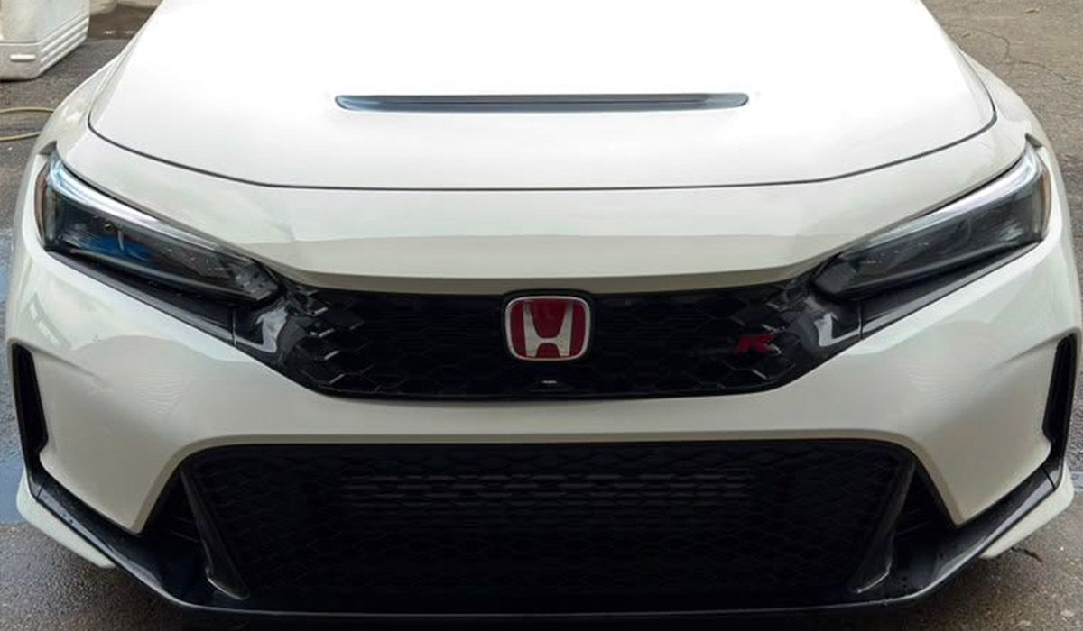 Front view of a white Honda car with a black grille and red emblem