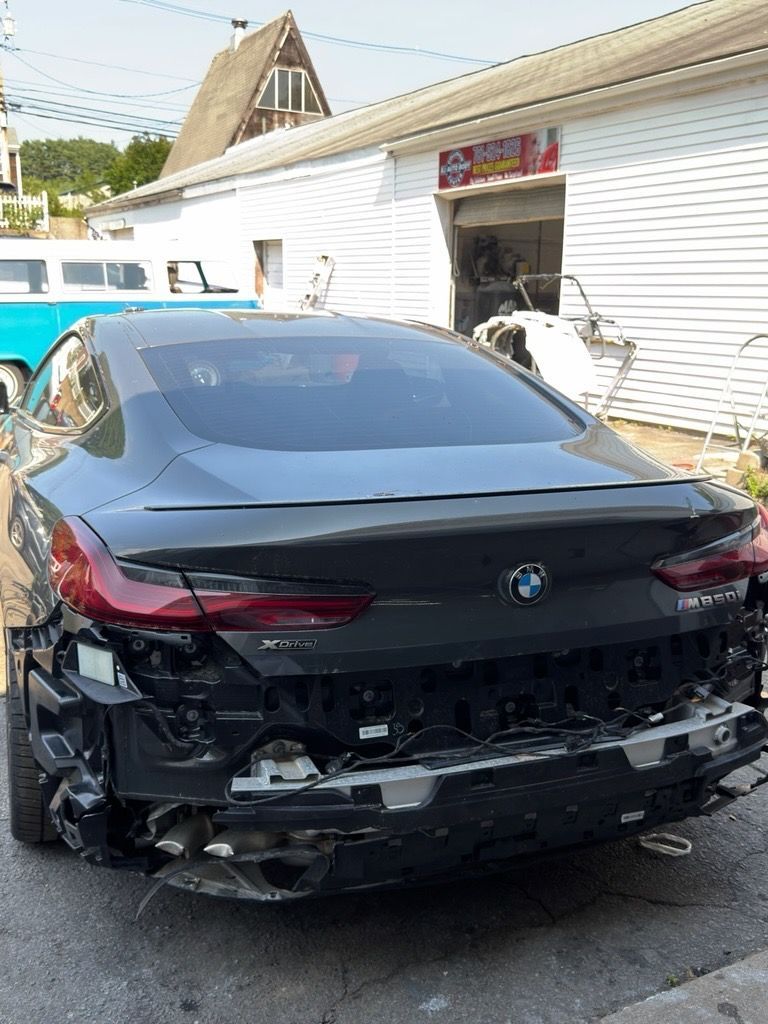 Black BMW with severe rear-end damage parked outside a white building