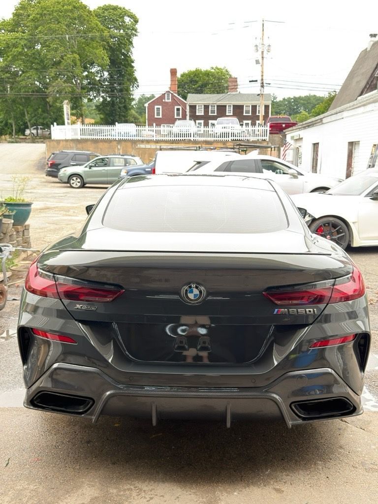 Black BMW sedan parked in a lot, rear view with white roof and tinted taillights.