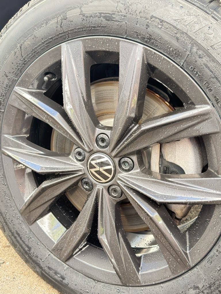 Close-up of a dirty Volkswagen alloy wheel with a flat tire and visible brake rotor