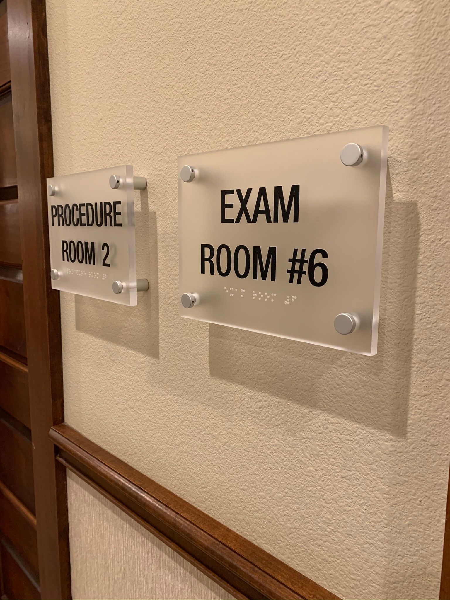 Hallway wall signs for Preorder Room 2 and Exam Room #6 mounted on beige textured wall