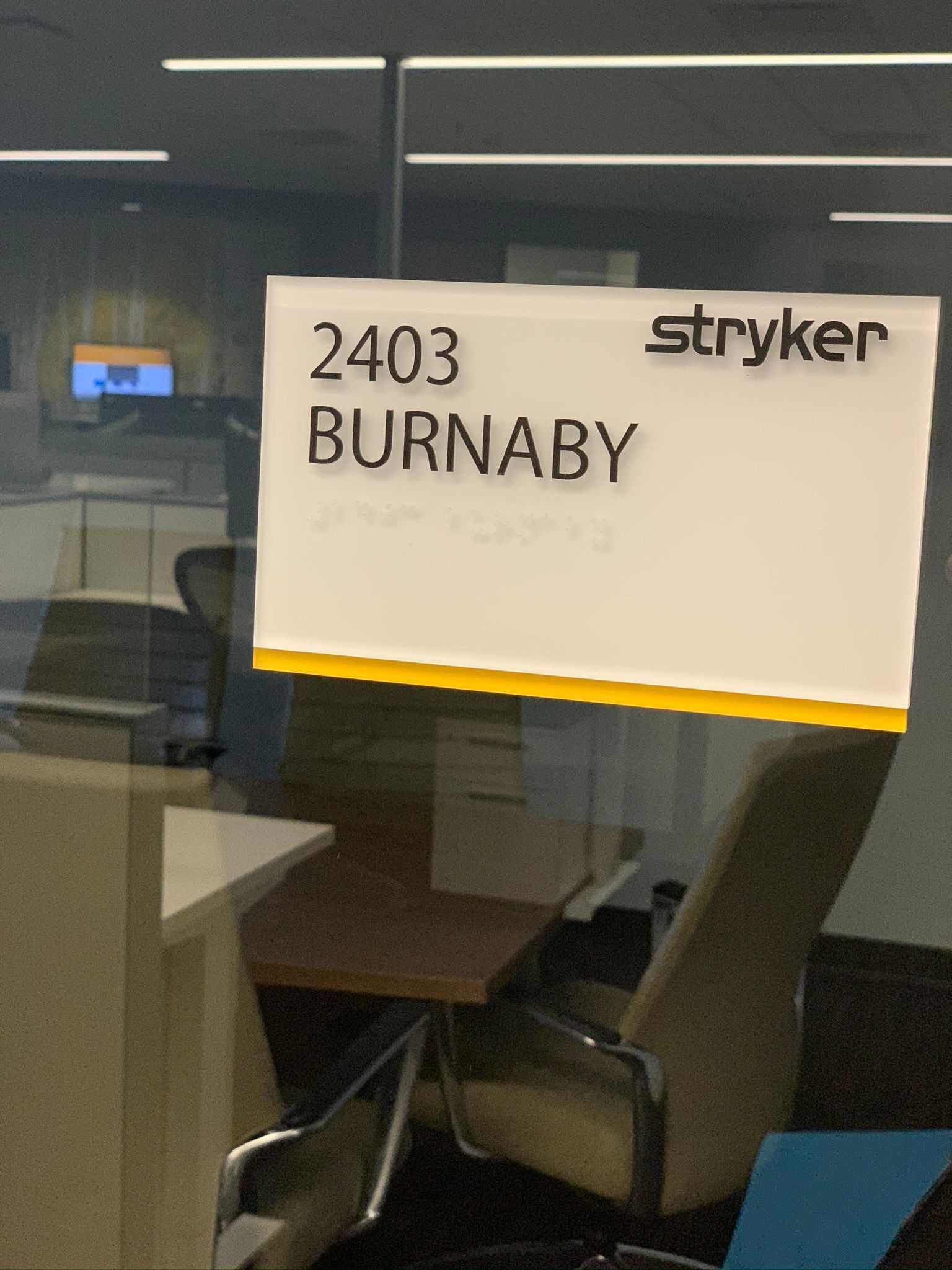 Office door sign reading “2403 BURNABY” with the Stryker logo on a glass door.