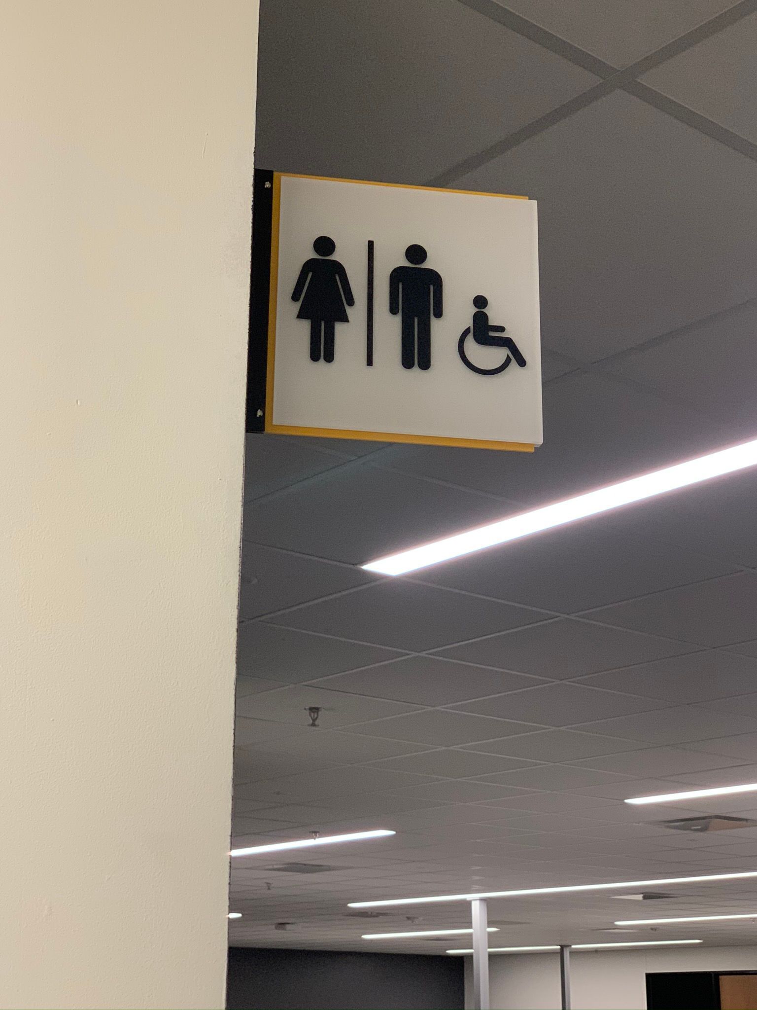 Restroom sign on wall with female, male, and wheelchair-accessible symbols