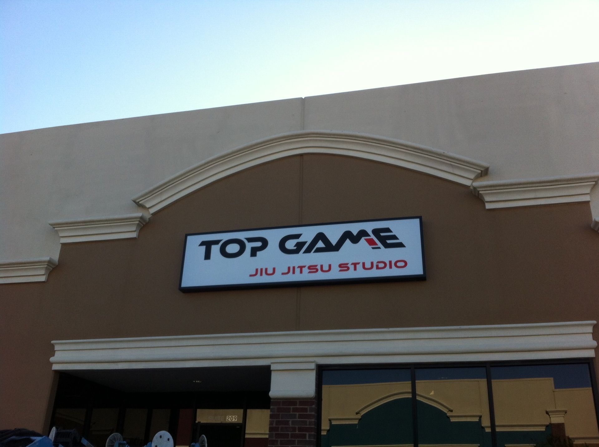 Storefront sign for Top Game Jiu Jitsu Studio on a beige building