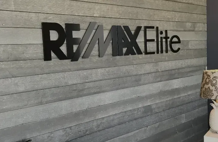 RE/MAX Elite sign on a gray textured wall
