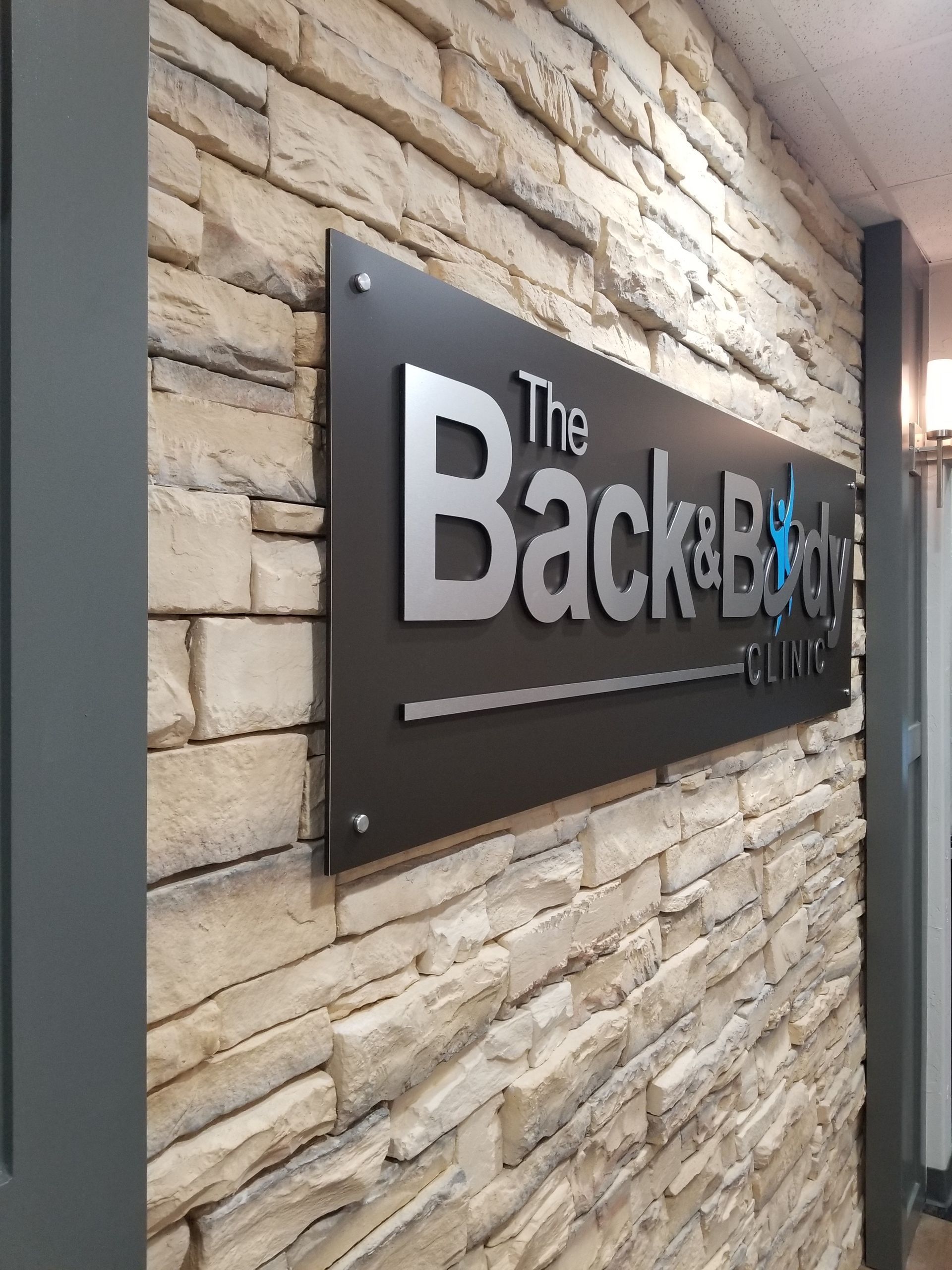 Wall sign reading “The Back Bar” on a stone wall in a hallway.