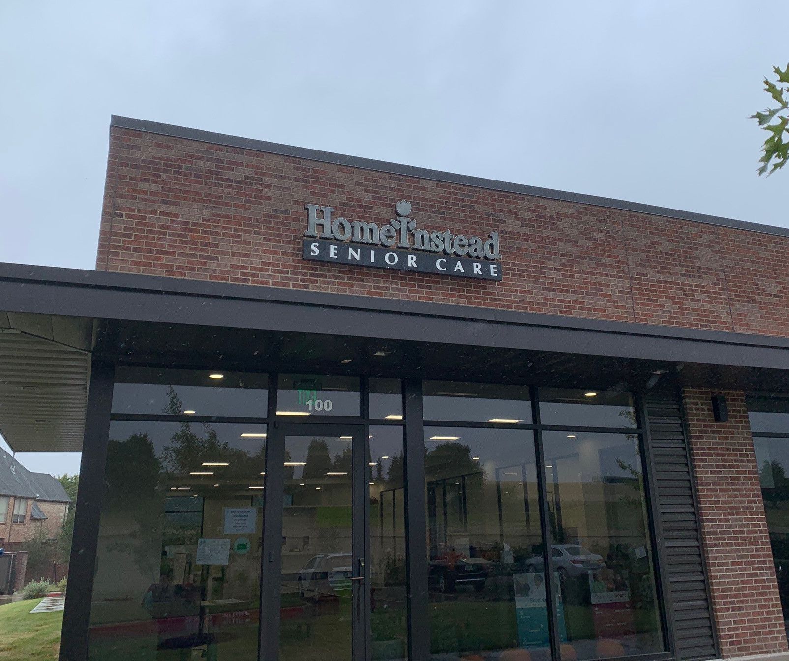 Brick storefront for Home Instead Senior Care with glass entrance and cloudy sky above