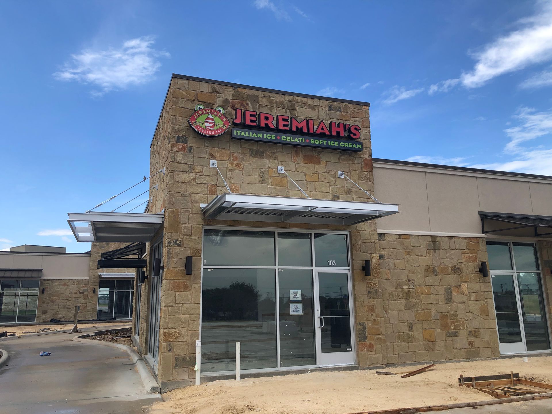 Jeremiah’s storefront with stone facade, glass entrance, and blue sky above