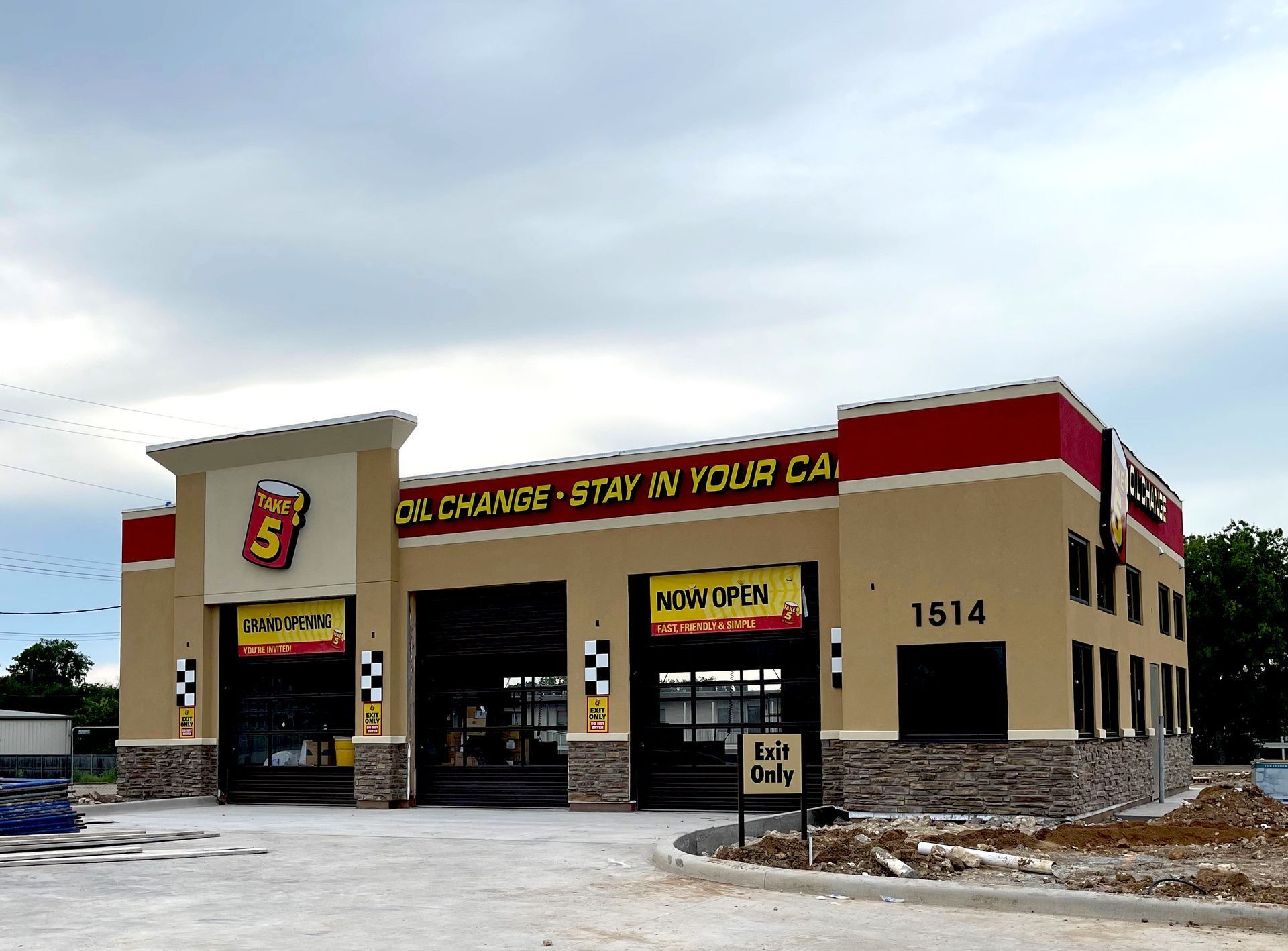 Small tan and red convenience store with a parking lot and snow on the ground