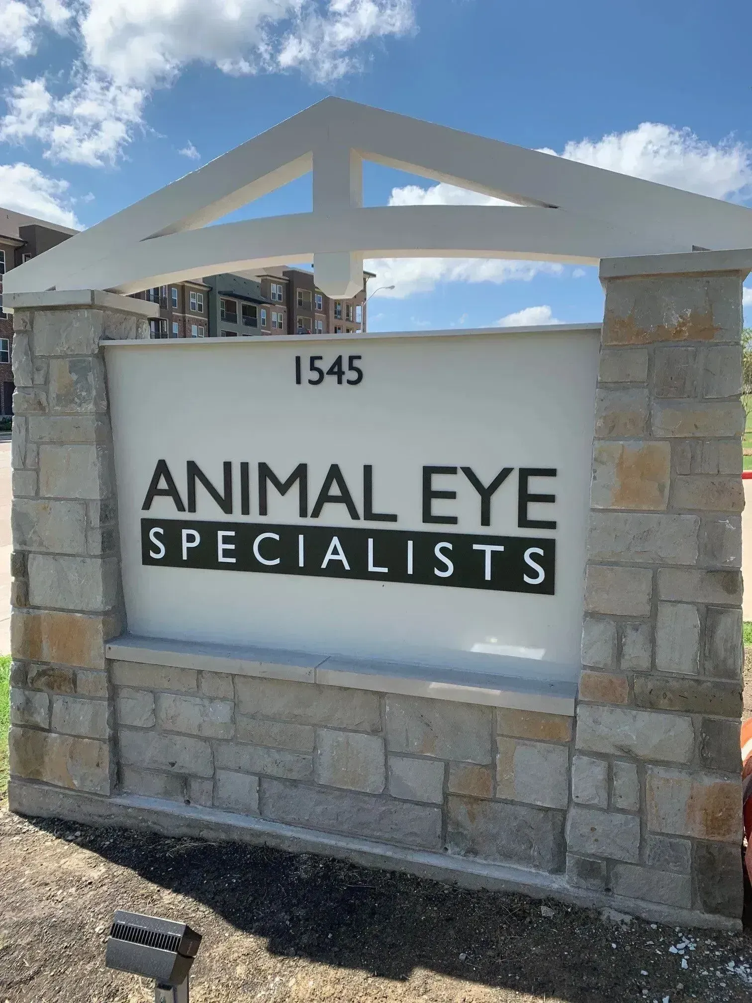 Animal Eye Specialists sign on stone wall with address 1545 under a blue sky.