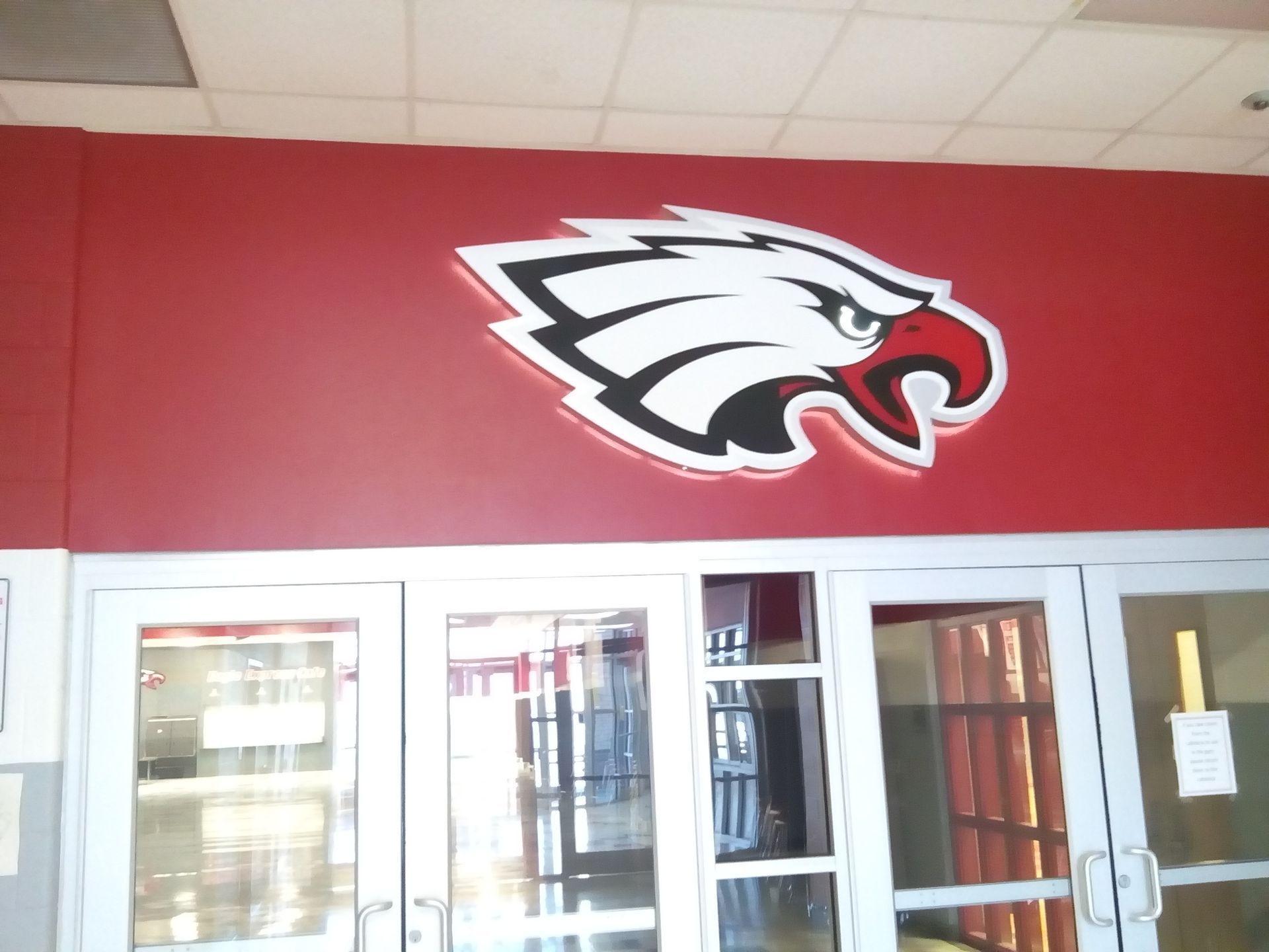 Red-and-white eagle logo above glass doors in a school hallway