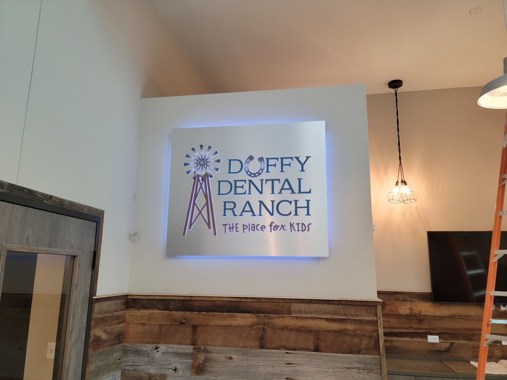 Duffy Dental Ranch sign mounted on a white wall above rustic wood paneling in a lobby