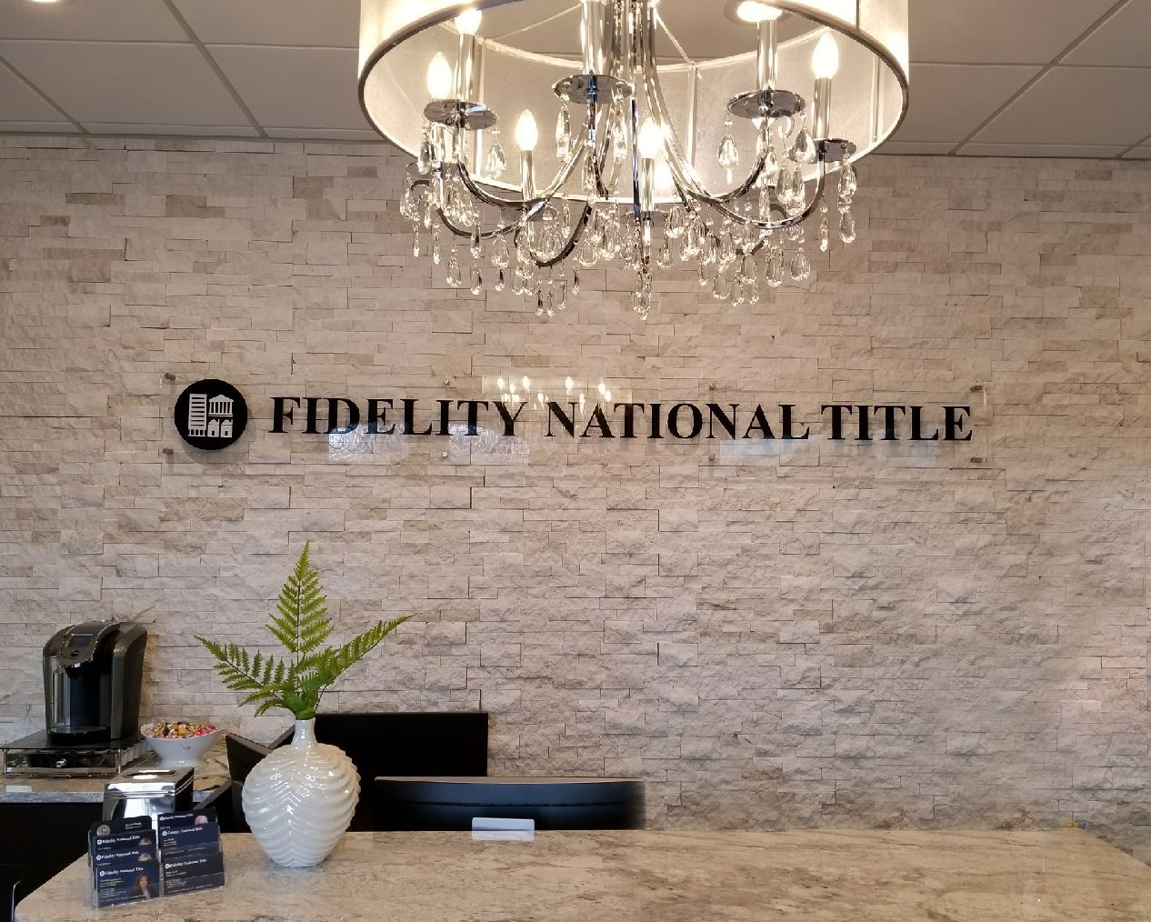 Fidelity National Title office reception desk with chandelier and stone accent wall