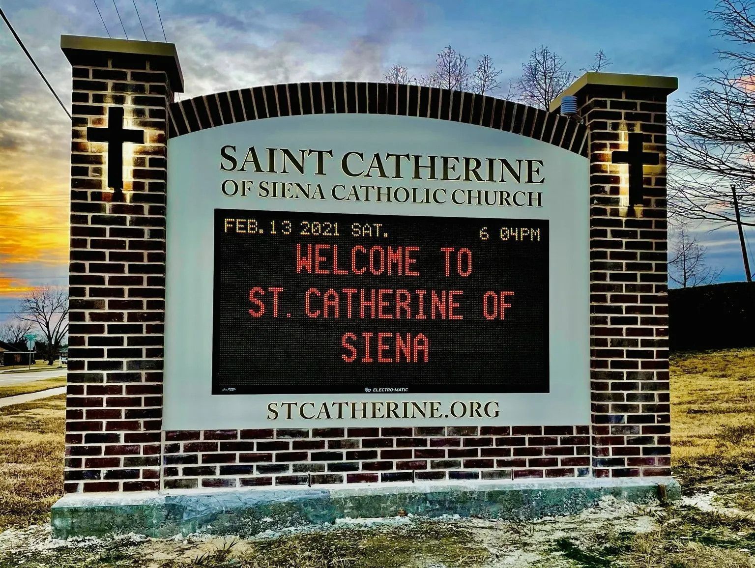Sign for St. Catherine of Siena Catholic Church with a welcome message displayed on an LED screen.