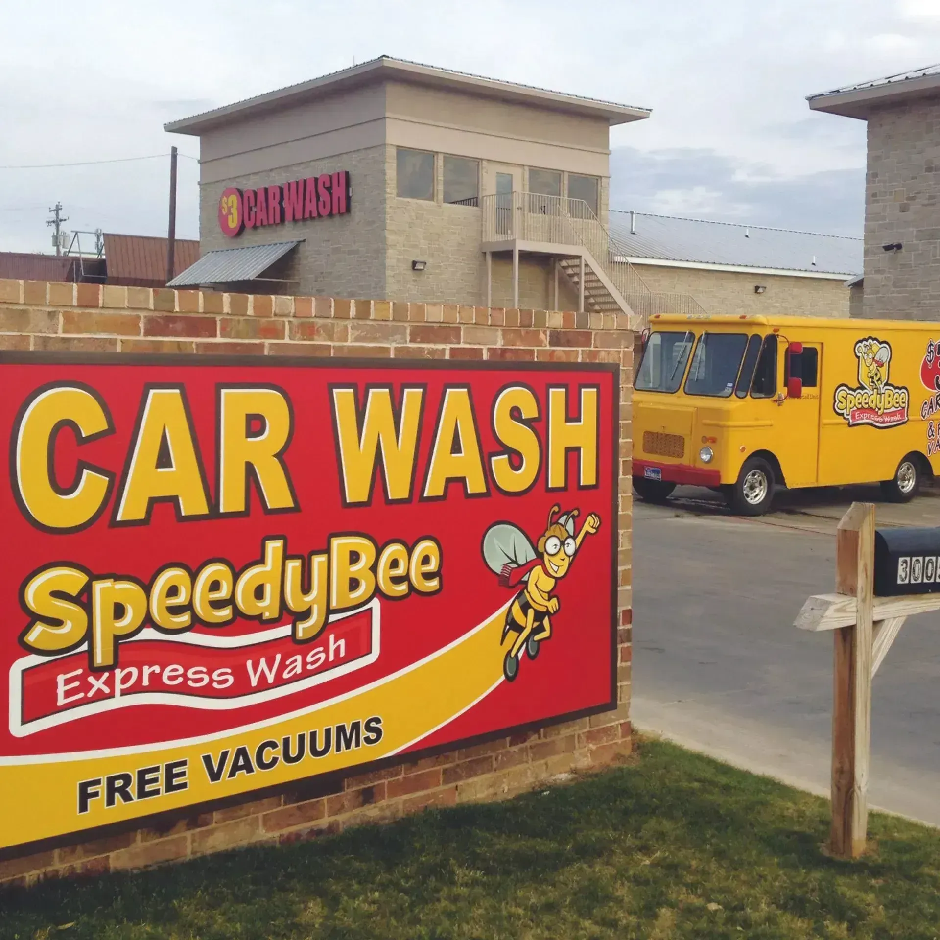 SpeedyBee Express car wash sign with yellow van in the background and free vacuums notice