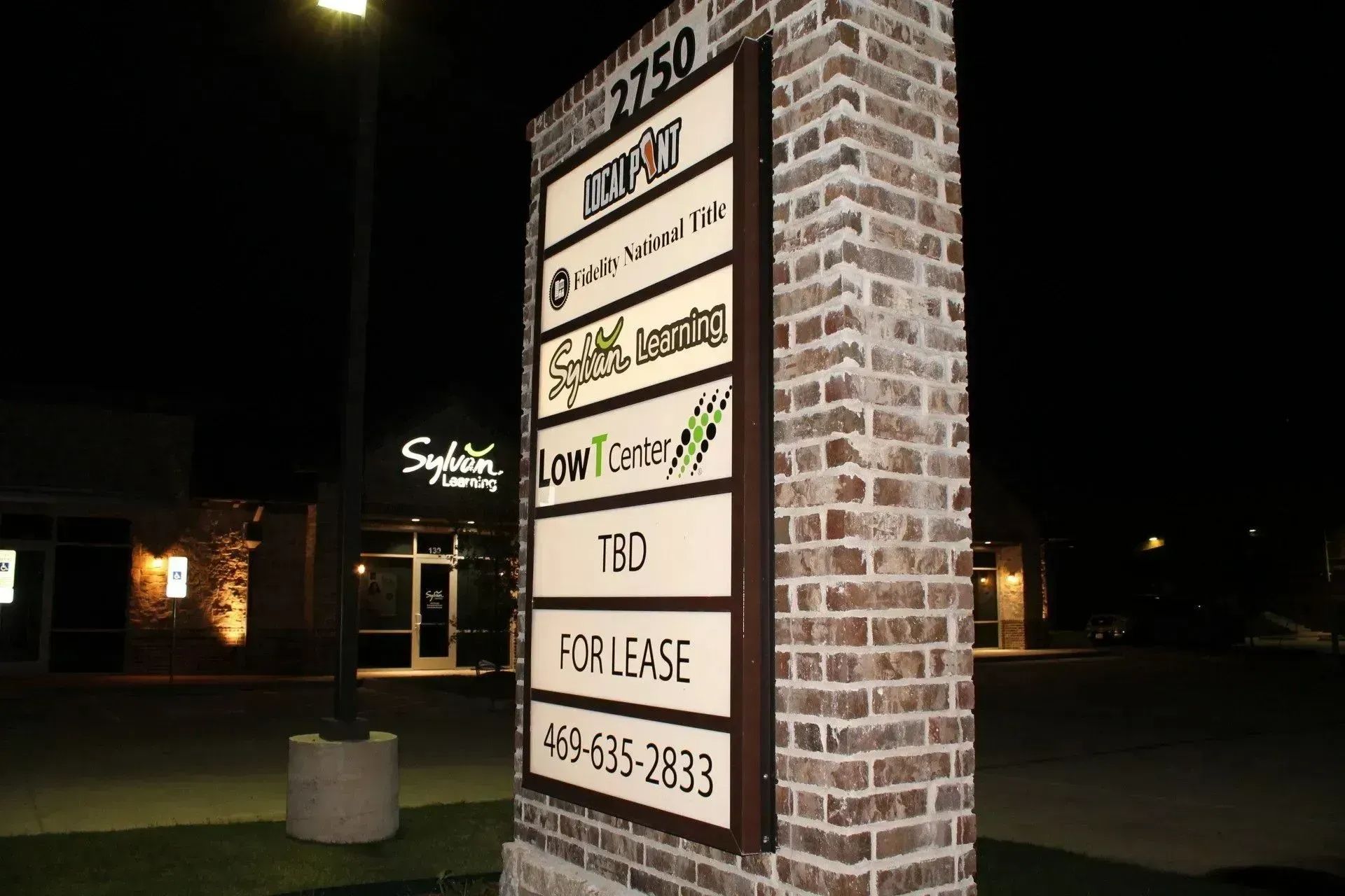 Multi-tenant brick monument sign with illuminated lightbox panels in Flower Mound, TX.