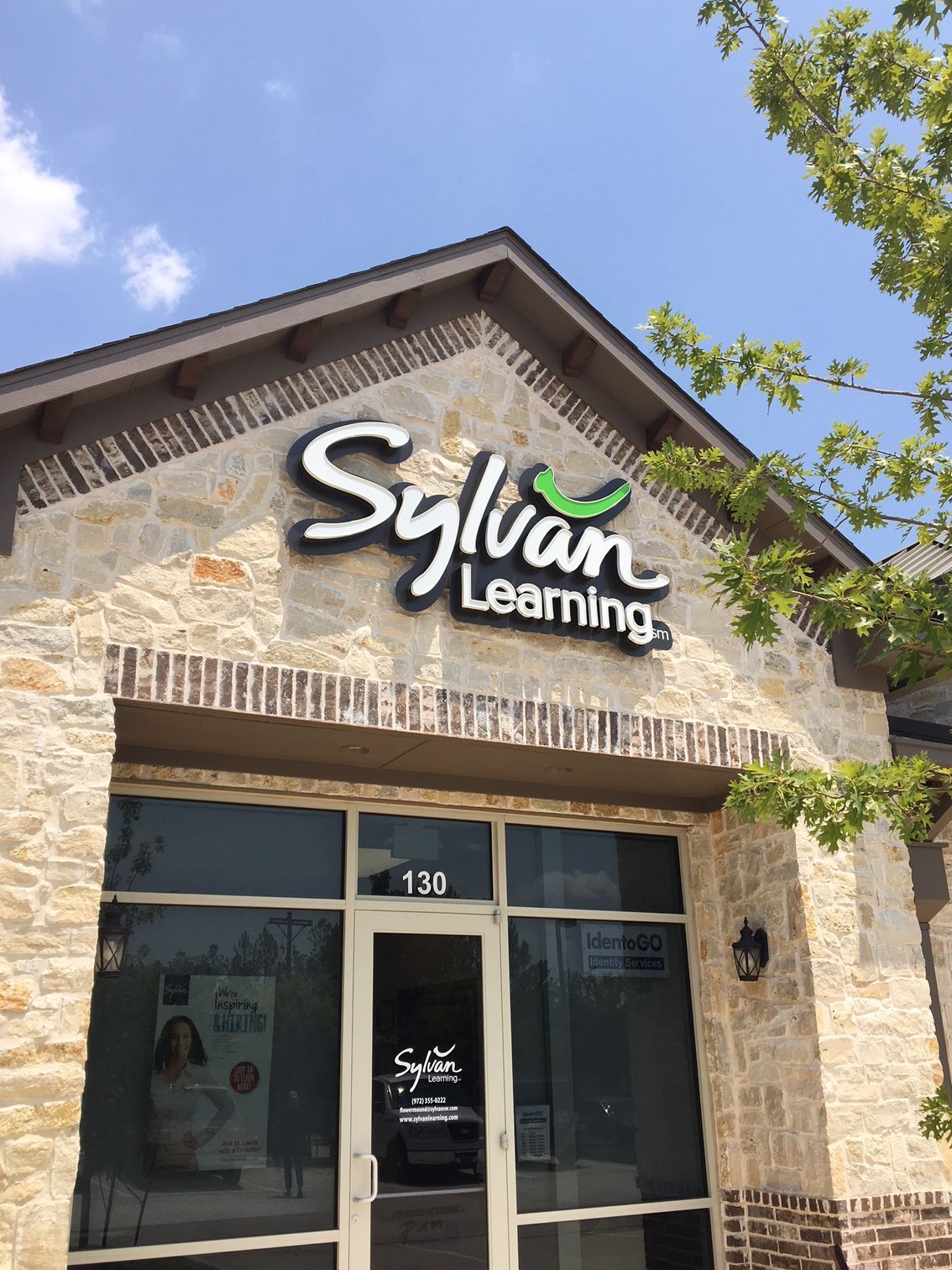Sylvan Learning storefront with stone facade, glass doors, and sign under a blue sky.