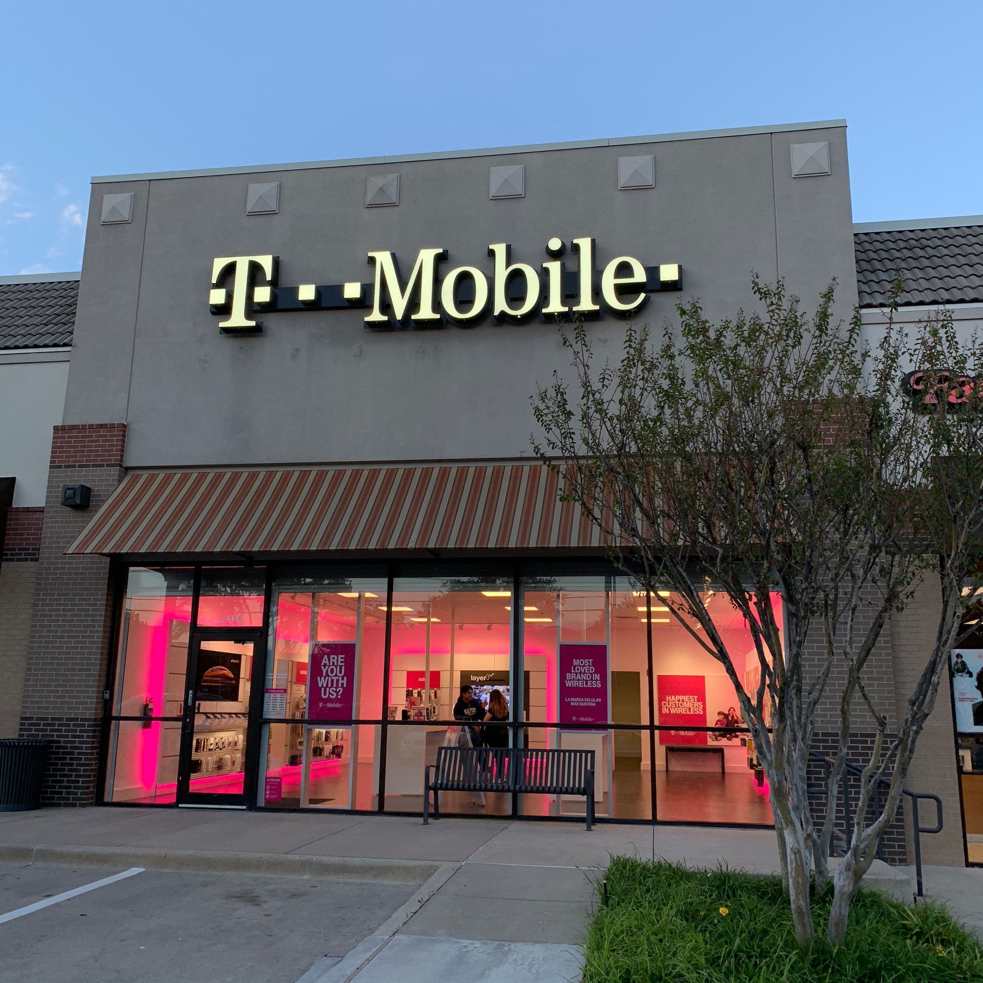 T-Mobile storefront at dusk with pink-lit windows and a glass entrance