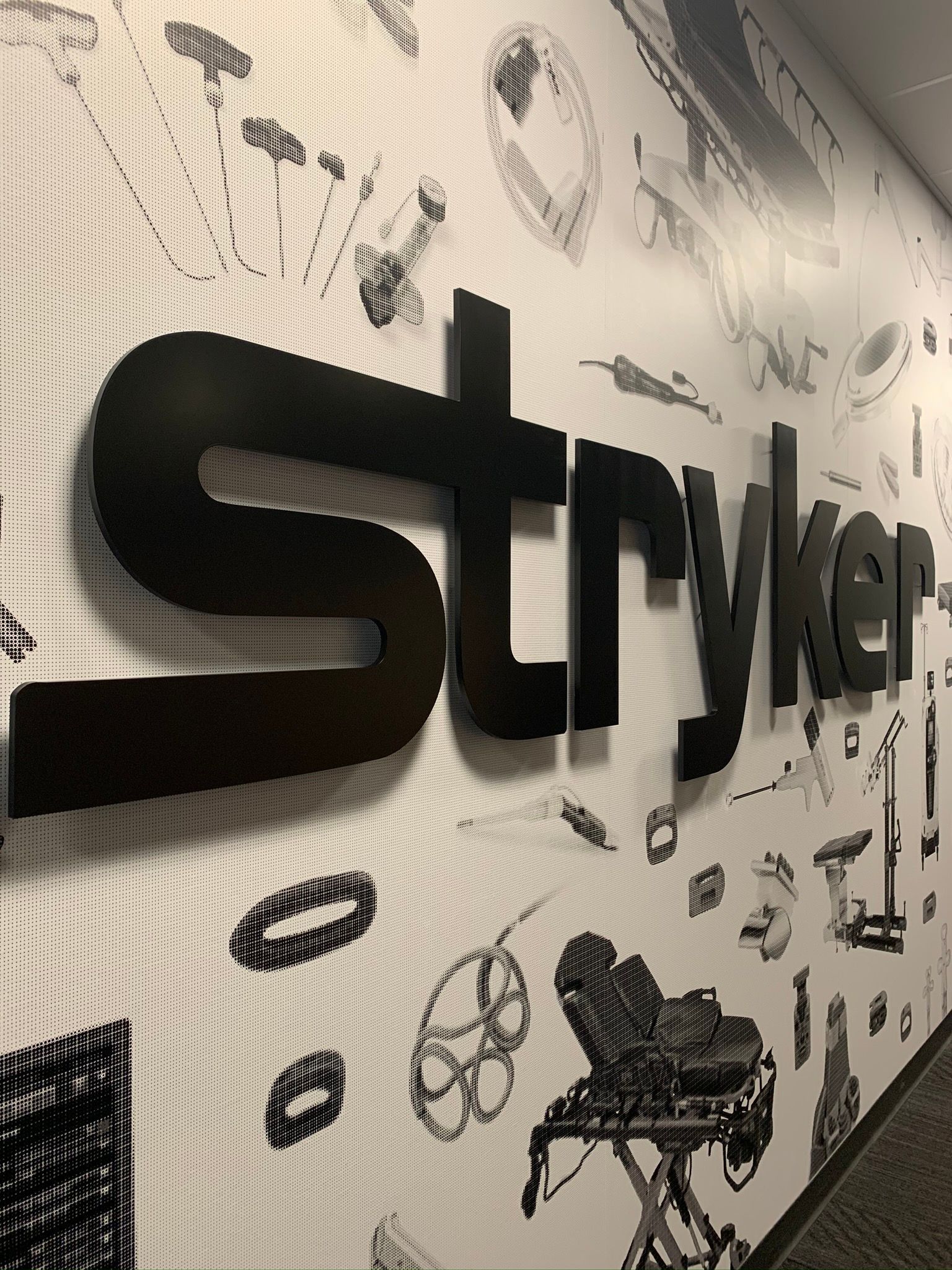 Black 3D “Striker” logo on a white wall with doodle-style graphics in a store or office interior
