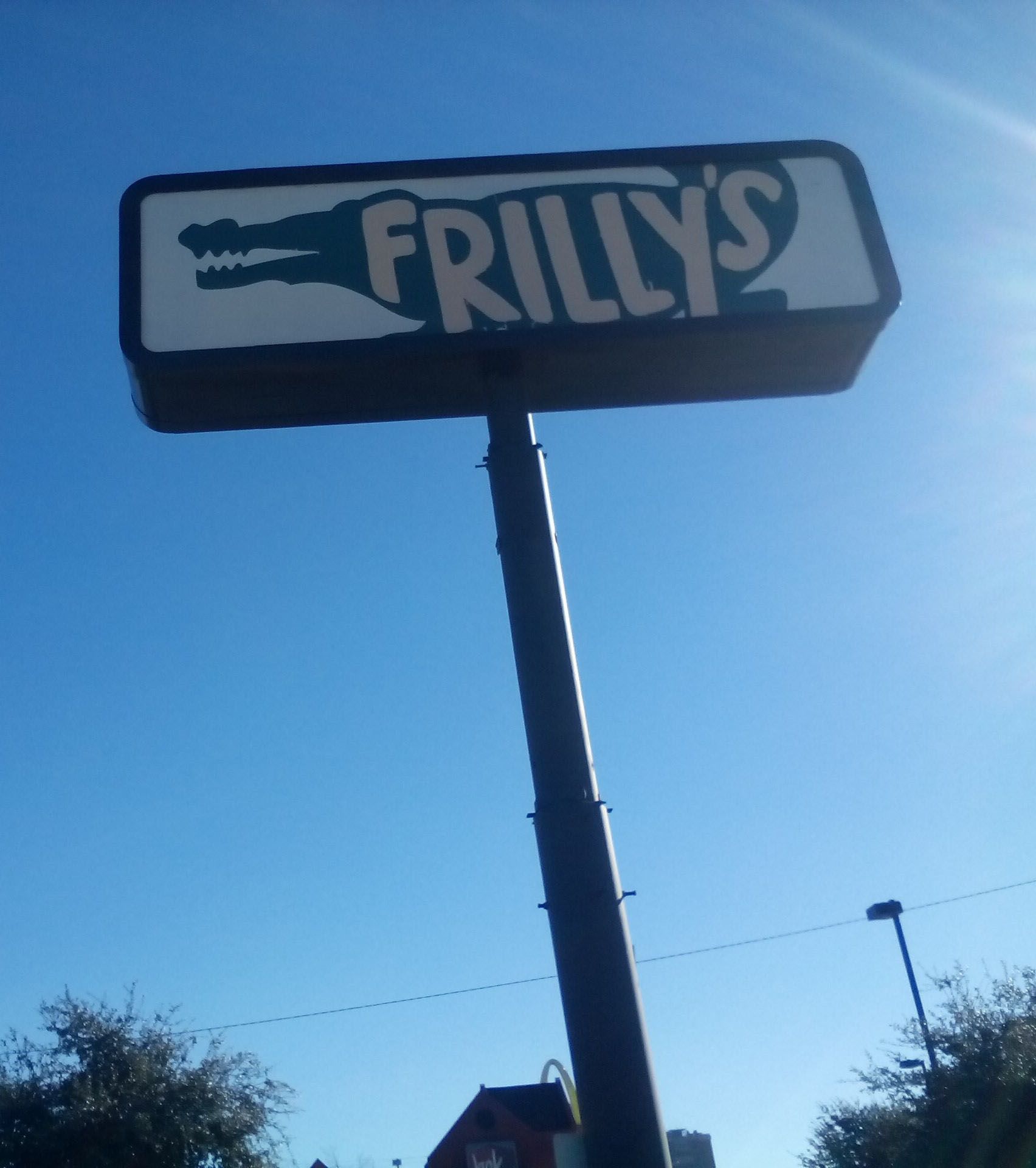 FRILLY’S sign on a tall pole against a clear blue sky