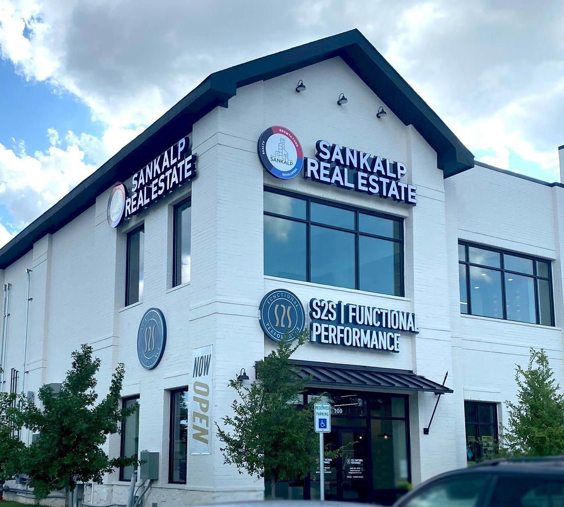 Front-lit channel letter signs for Sankalp Real Estate on a white brick building in Frisco, TX.