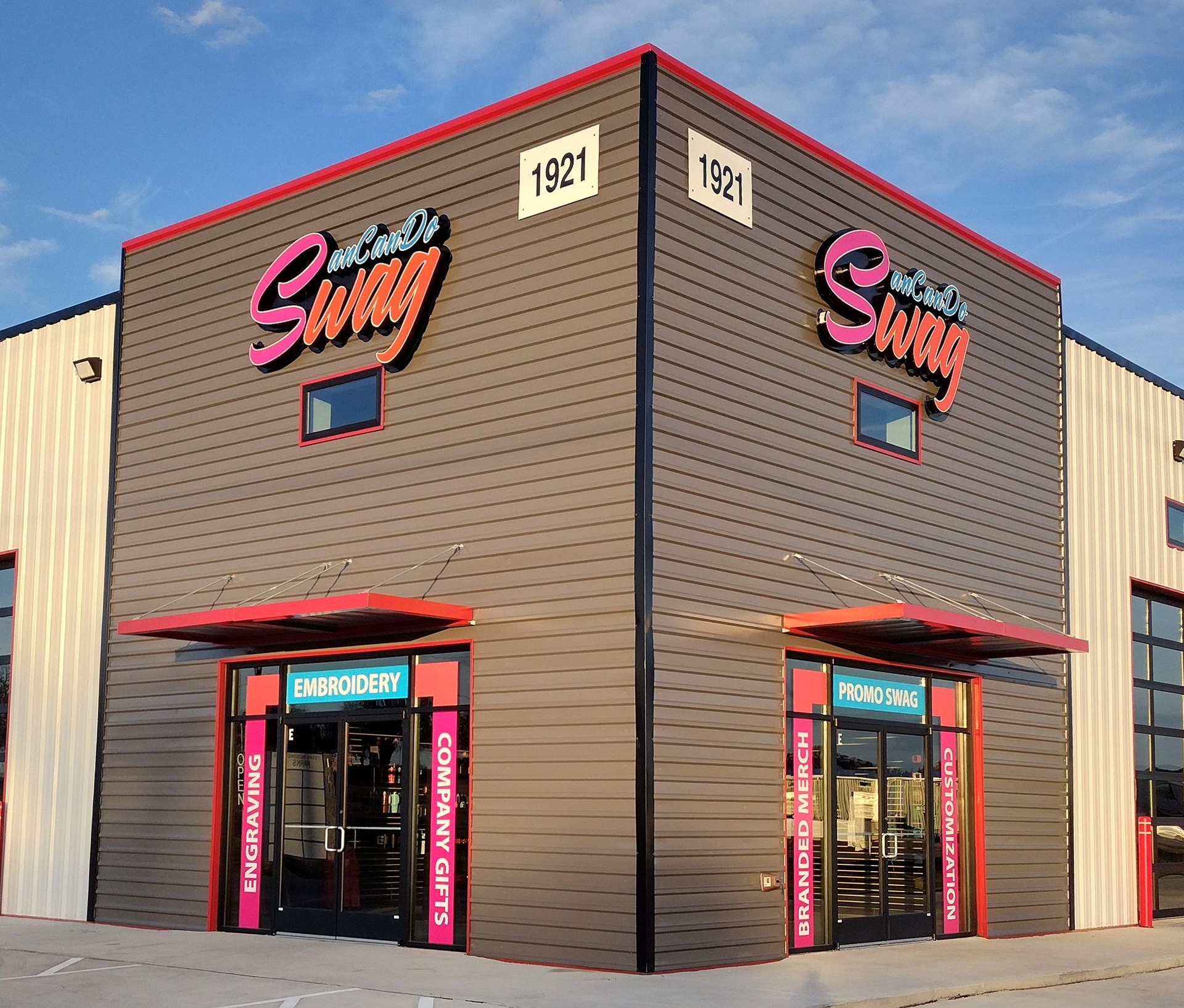 Corner storefront of “Swig” with pink signage, red awnings, and two entrance doors on a beige building.