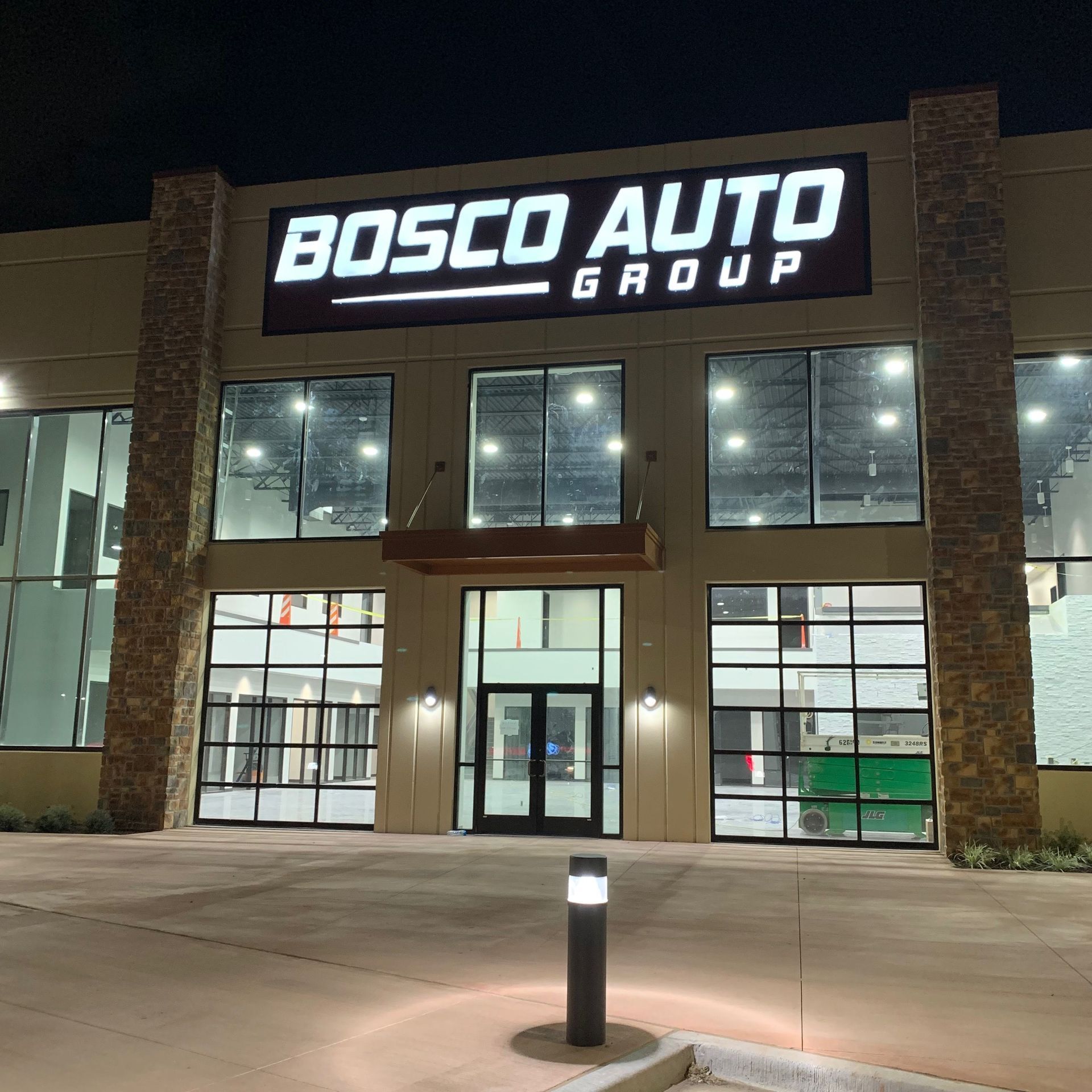 Illuminated Bosco Auto Group building sign at night in Flower Mound, TX.