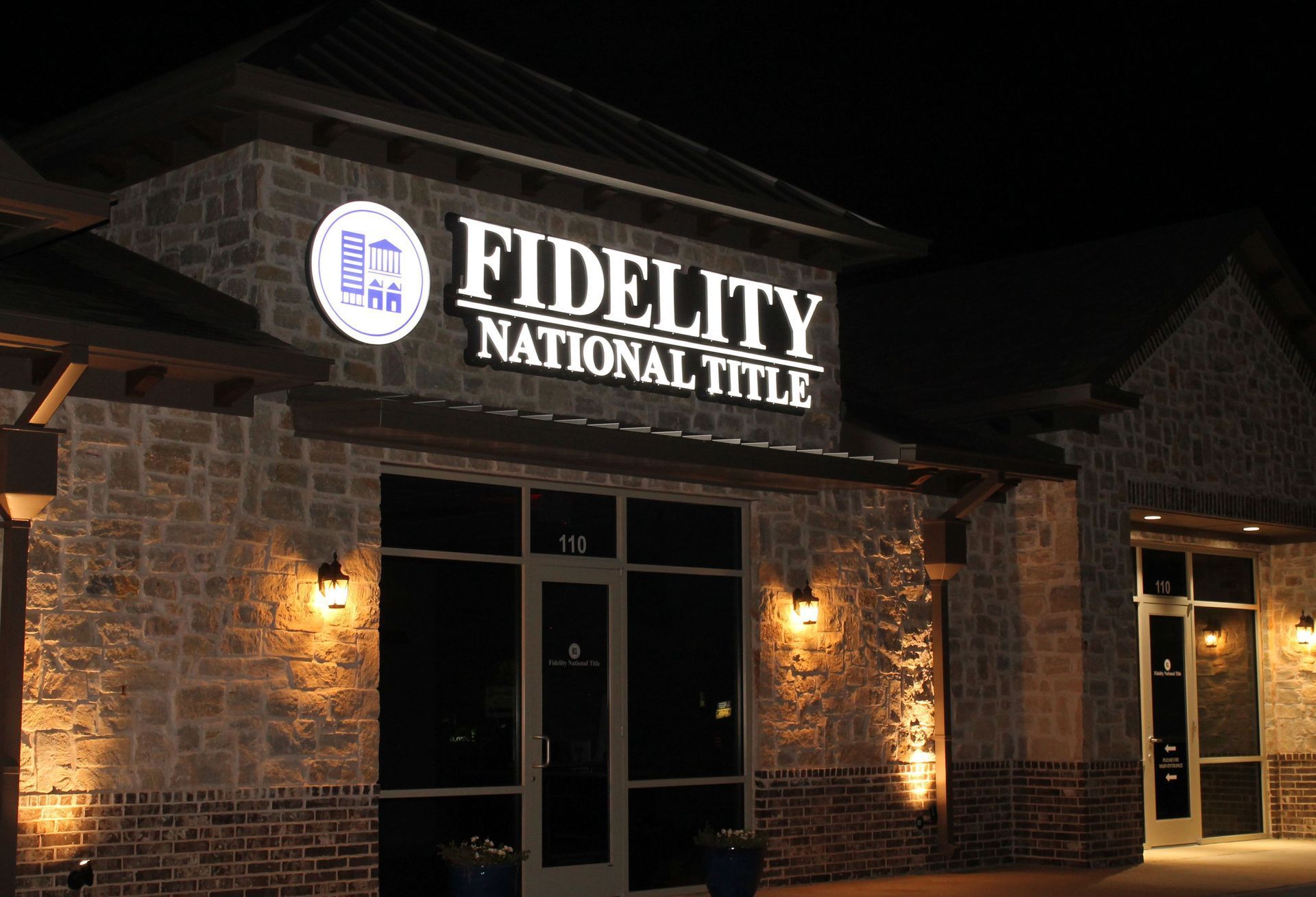 Illuminated channel letter and logo sign for Fidelity National Title photographed at night.