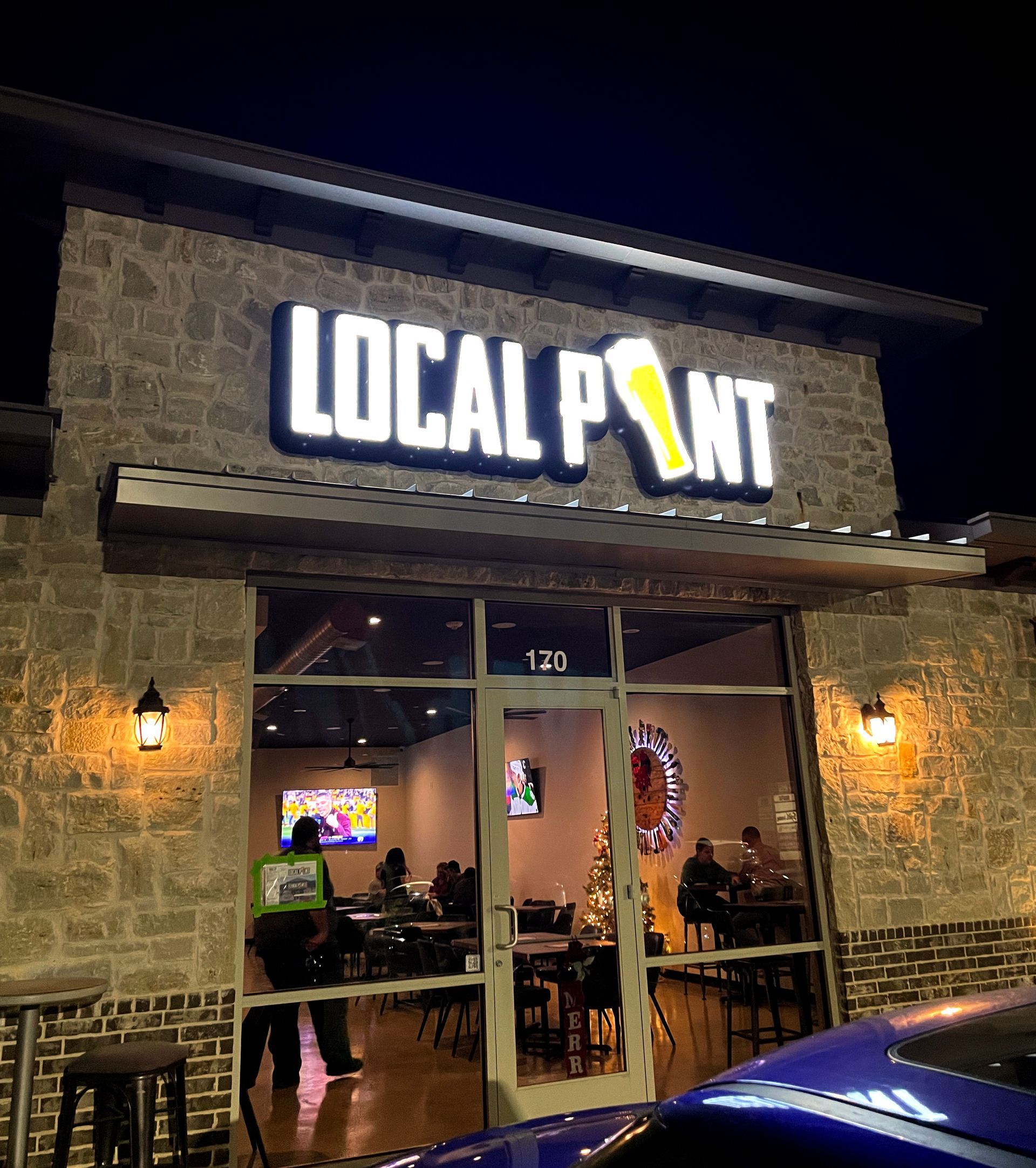 Local Point bar at night with illuminated sign and patrons inside.