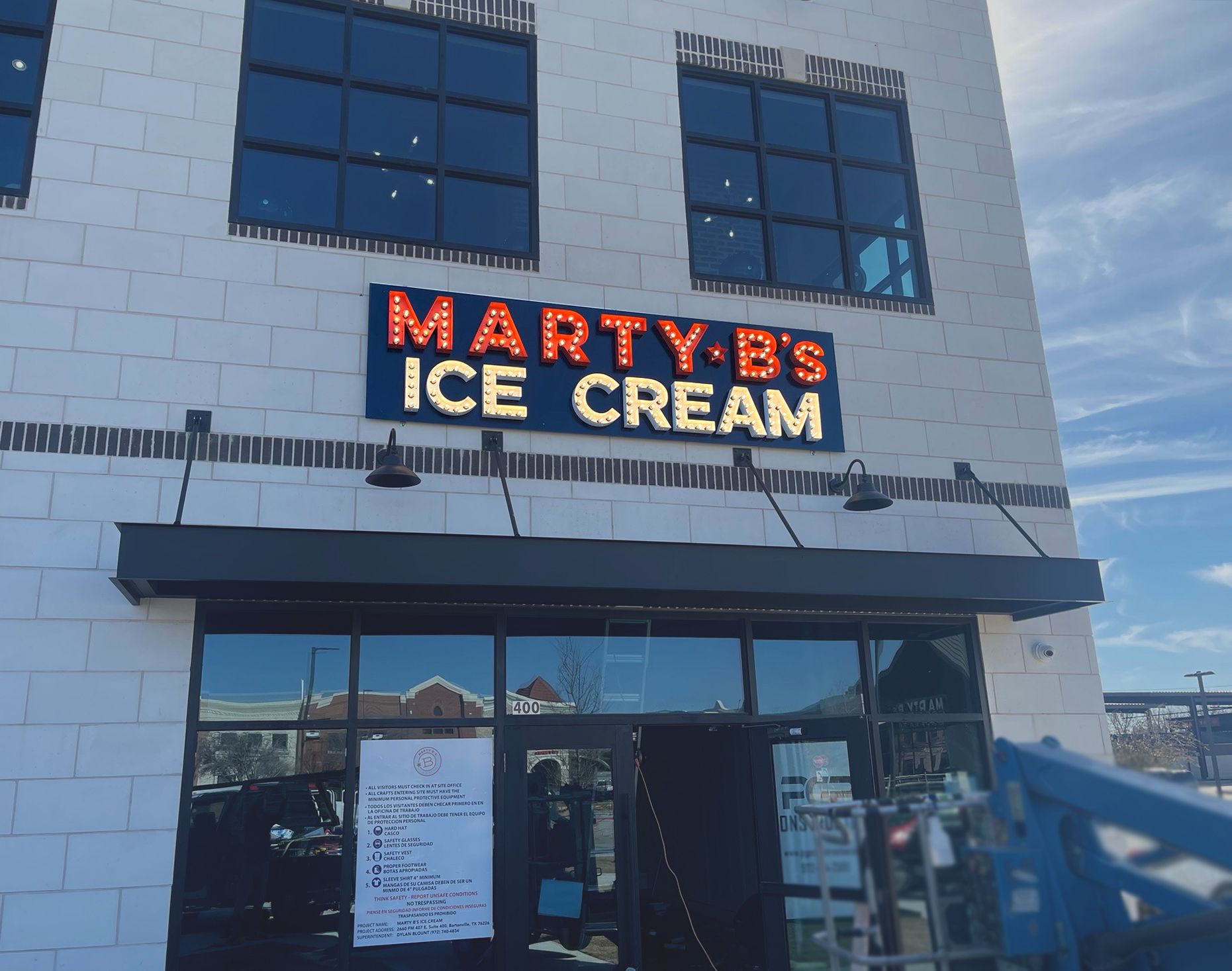 Marty B's Ice Cream storefront with a lit-up sign on a brick building, under a black awning.