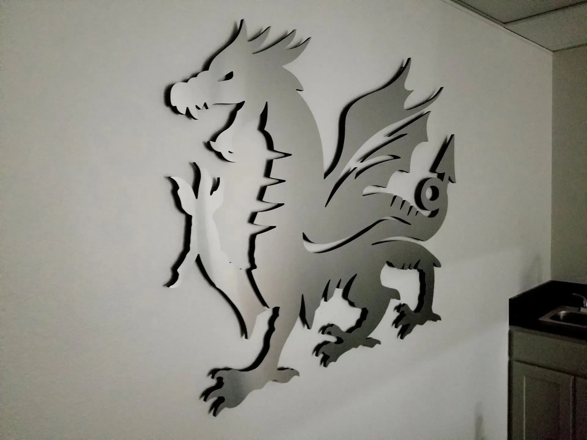 Silver dragon wall art on a white wall.