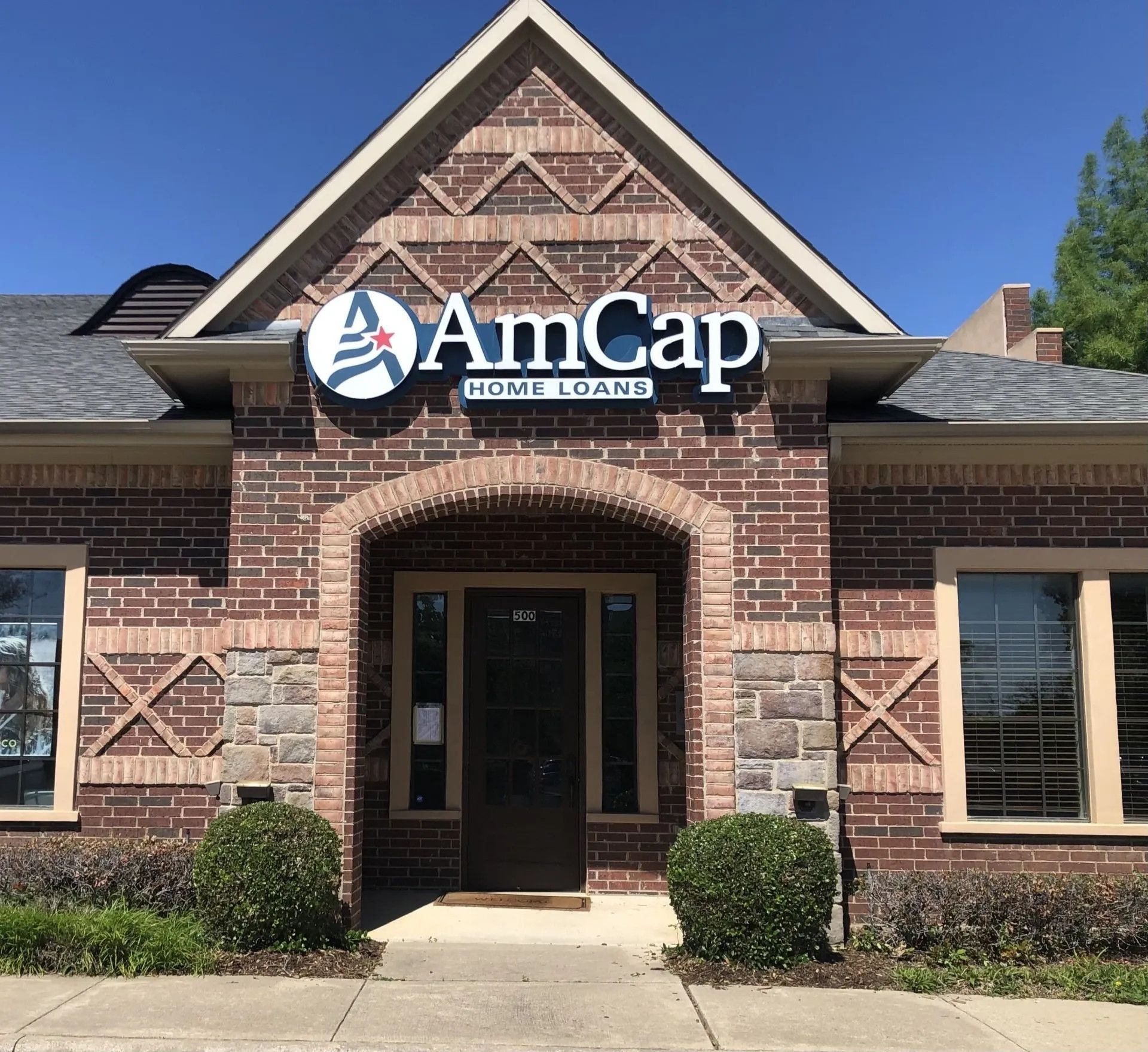 AmCap Home Loans storefront with brick exterior, windows, and sign.
