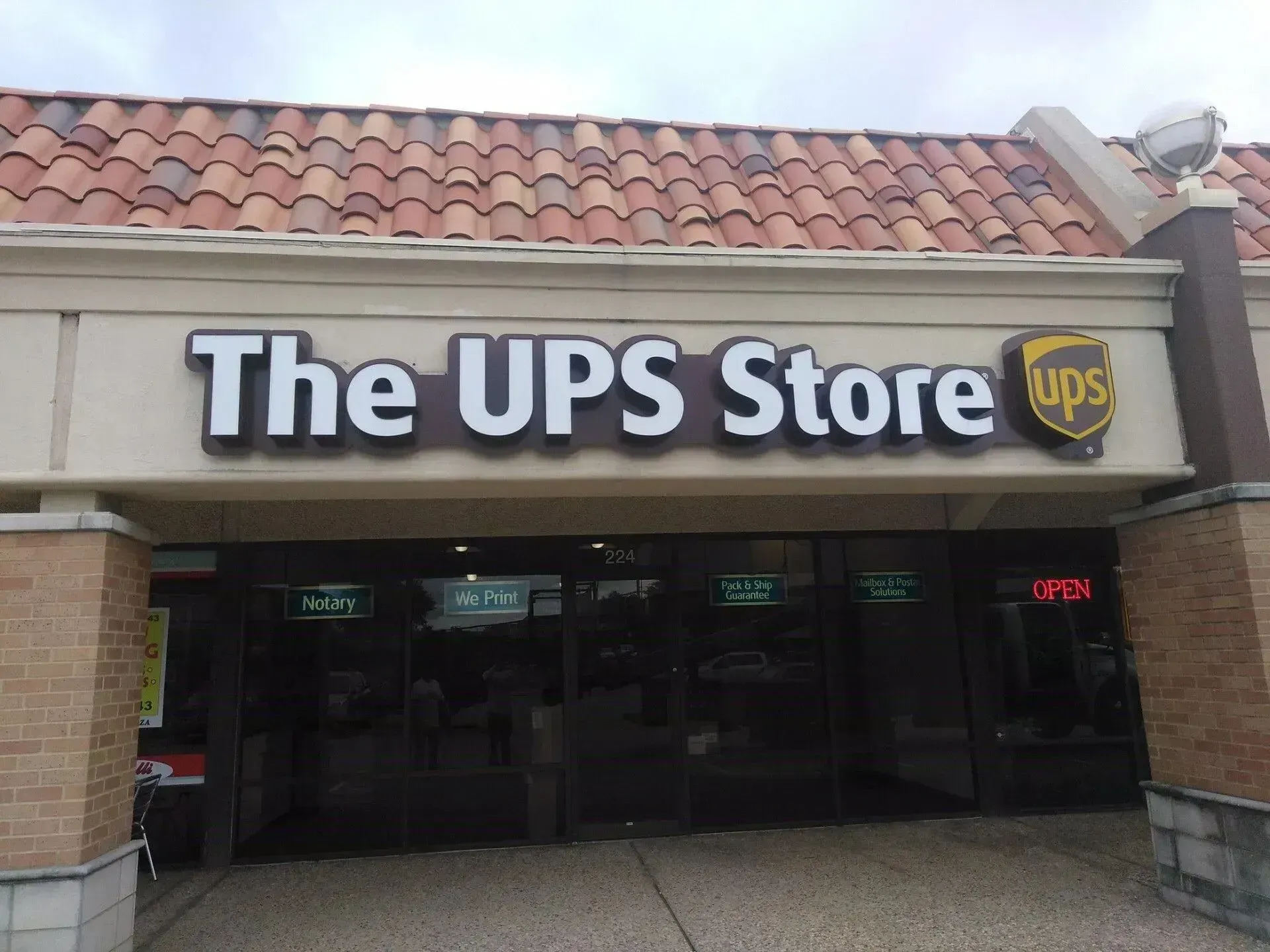 The UPS Store storefront with brown sign and logo above dark entrance doors.
