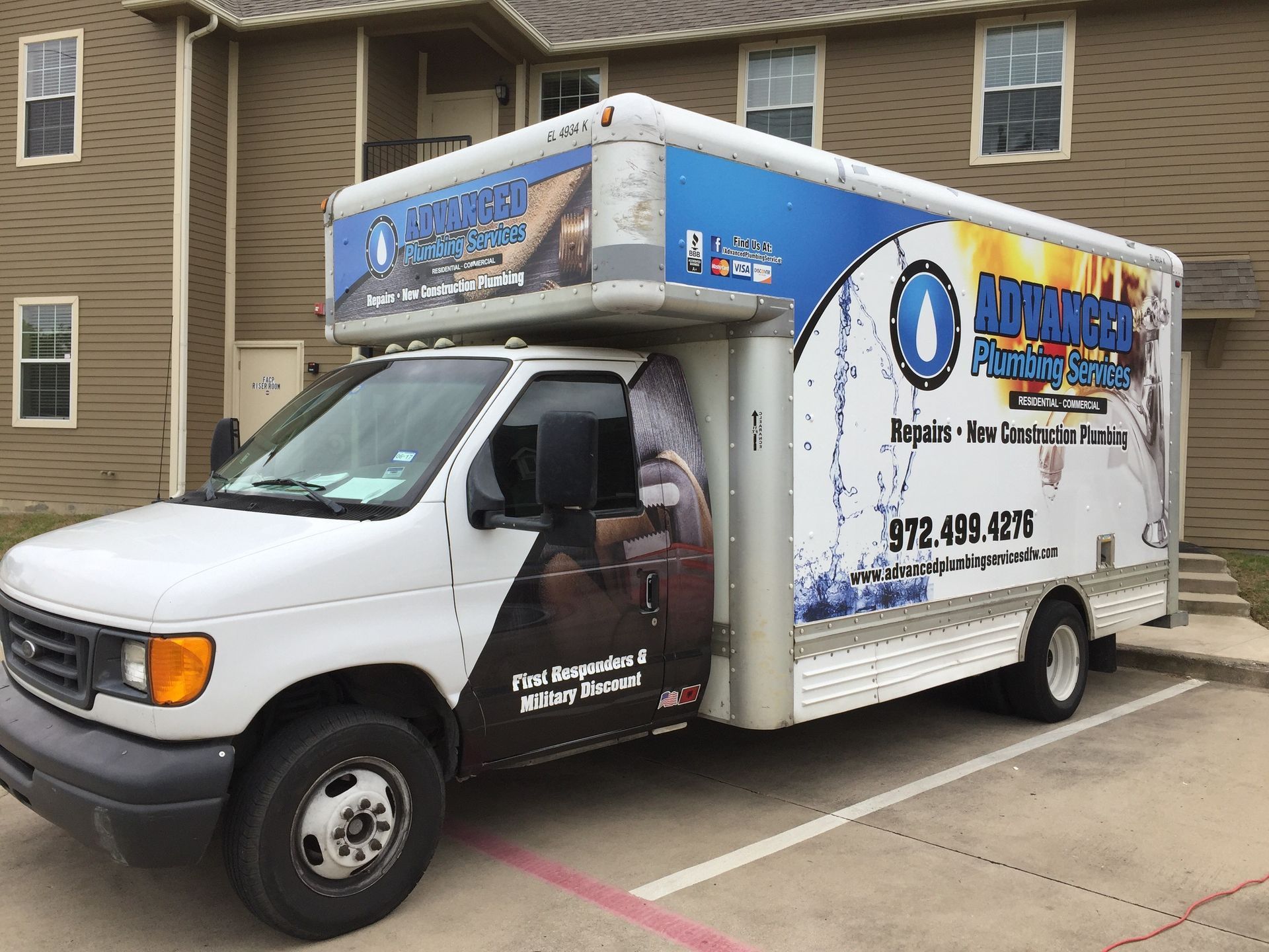 White moving truck with blue signage parked in a residential apartment lot