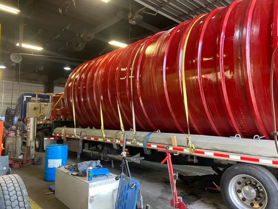 Large red cylindrical tank secured on a flatbed trailer, ready for transport.