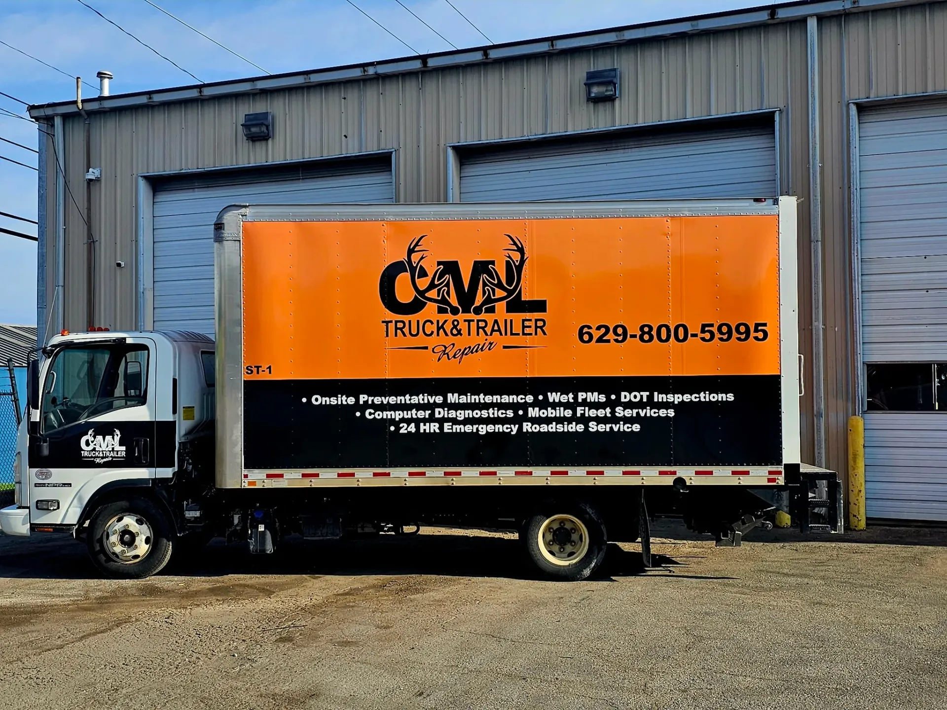 Box truck with orange side advertising CML Truck Trailer, parked in front of a building.