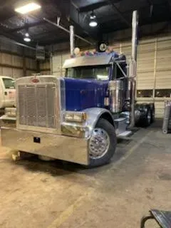 Blue and chrome Peterbilt semi-truck parked inside a garage.