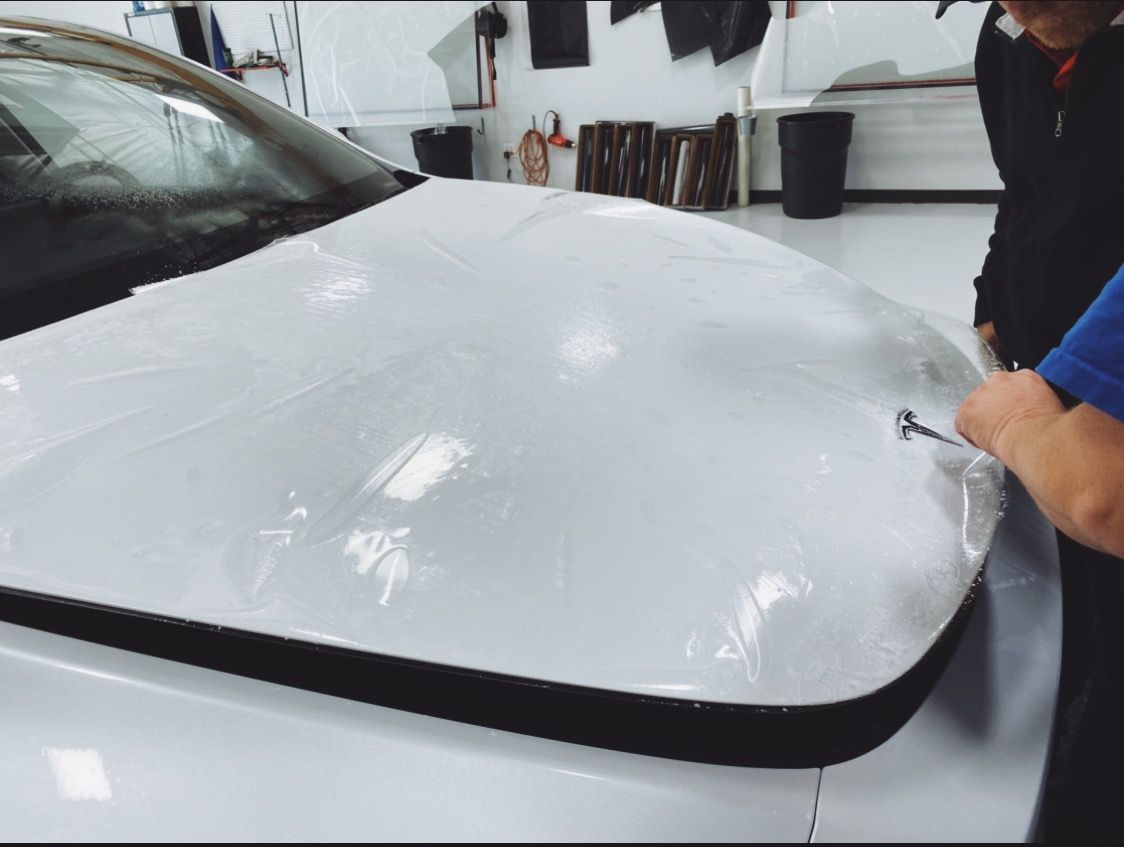 a man is wrapping the hood of a white car