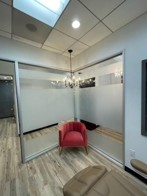 a room with a red chair, a couch, and a frosted glass wall
