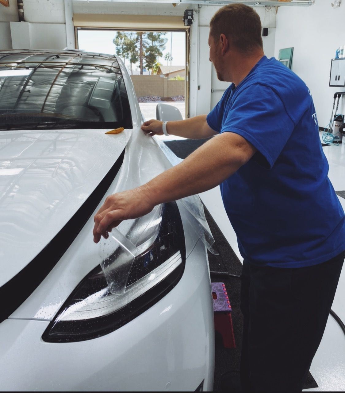 a man in a blue shirt is working on a white car
