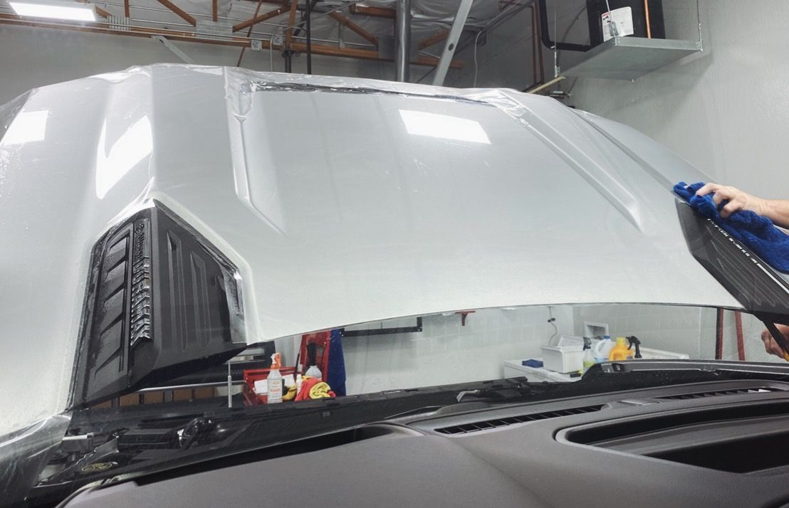 a person is cleaning the hood of a car in a garage