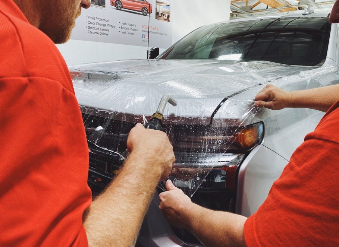 two men are wrapping a car with a protective film