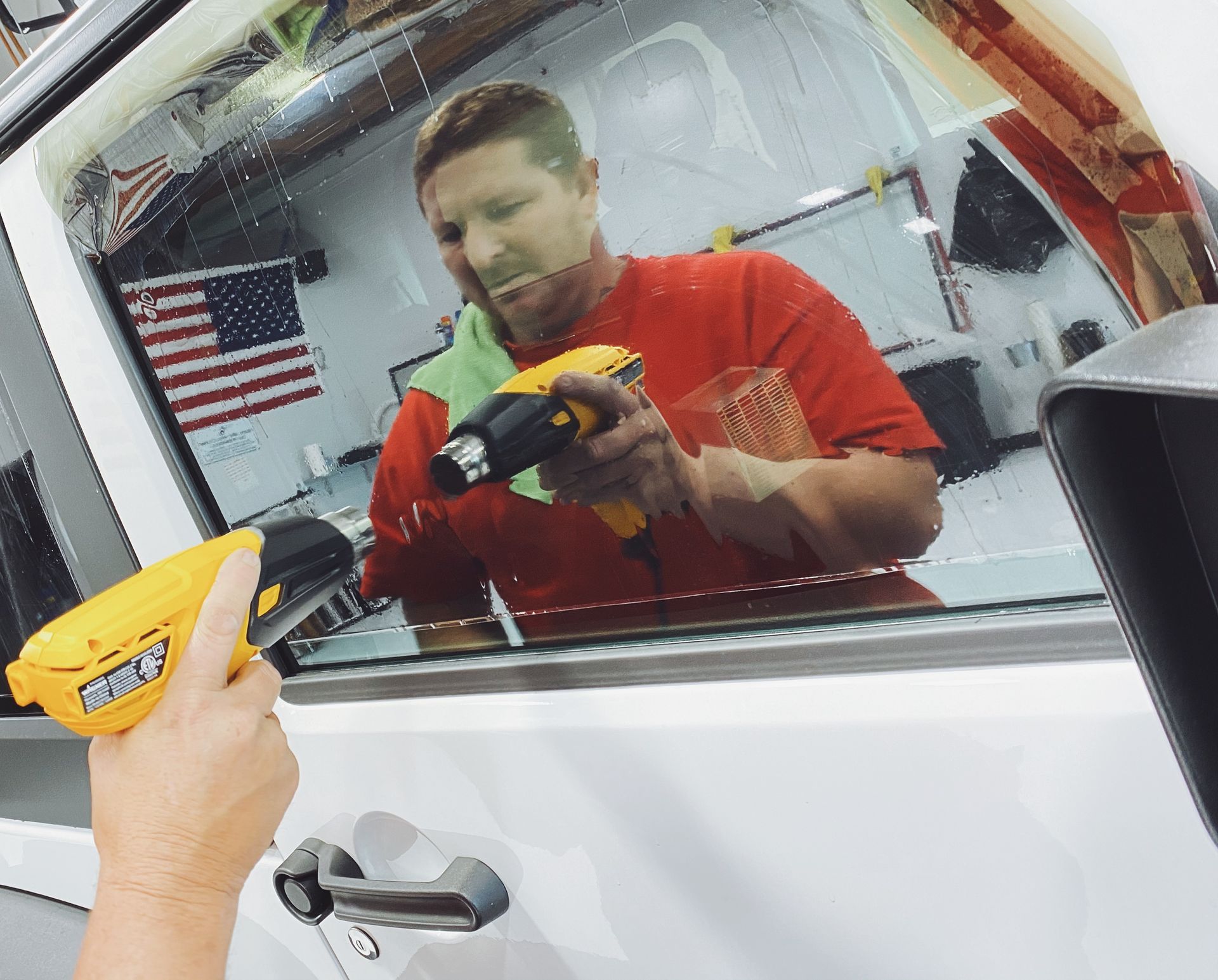a man in a red shirt is working on a car window